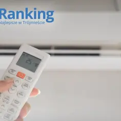 Dłoń trzymająca pilot do klimatyzacji ustawionej na 25°C, na tle białego urządzenia.