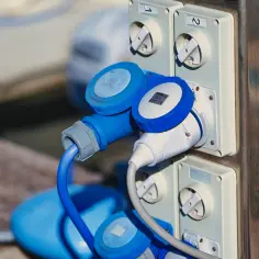 Wtyczki i gniazda elektryczne w kolorze niebieskim i białym, podłączone do panelu.
