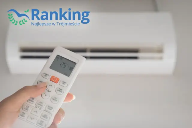 Dłoń trzymająca pilot do klimatyzacji ustawionej na 25°C, na tle białego urządzenia.